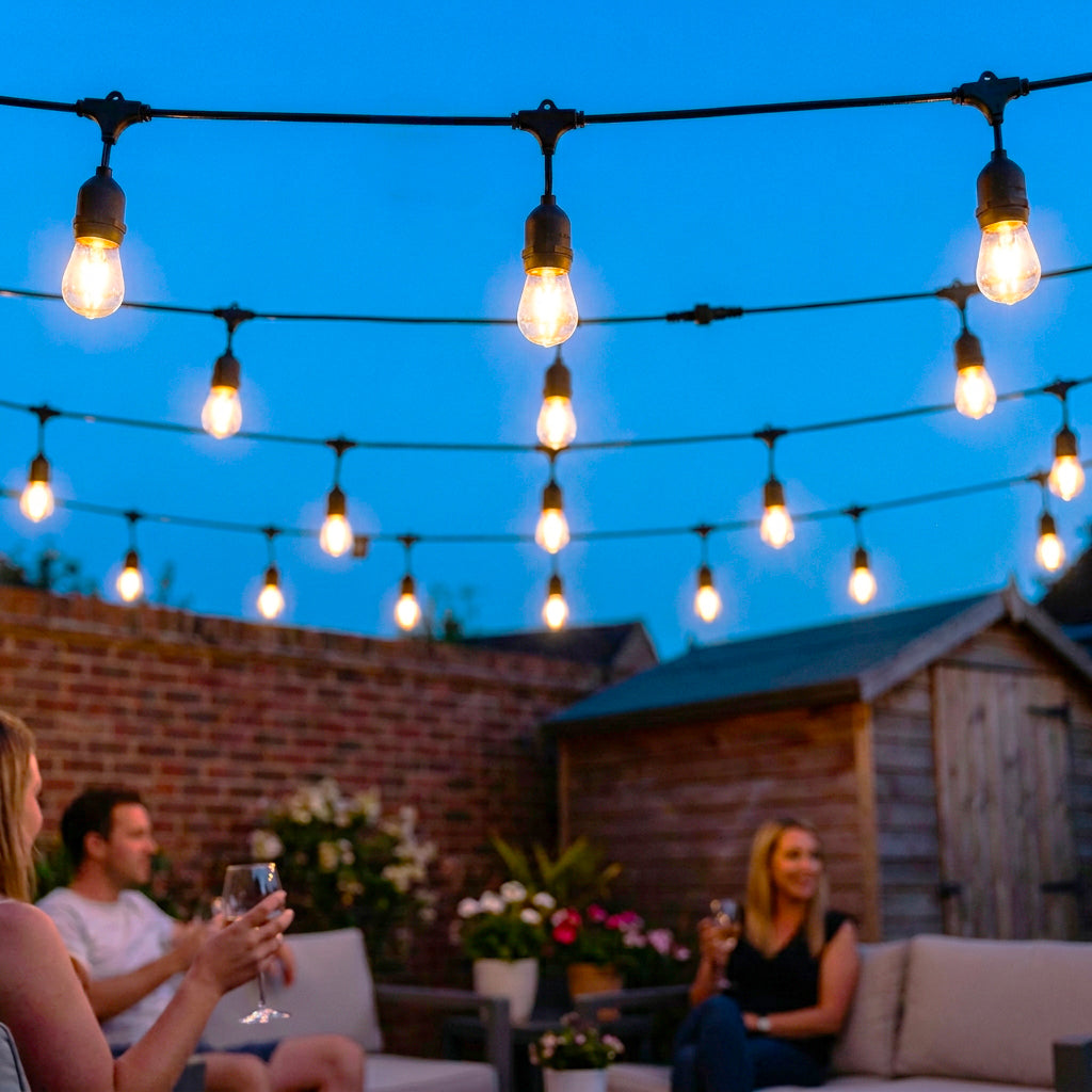 String lights hanging above a group of people on a patio at night.