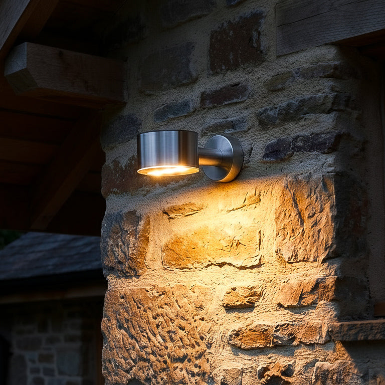 Outdoor wall light fixture on a stone building exterior solar down facing warm light silver body