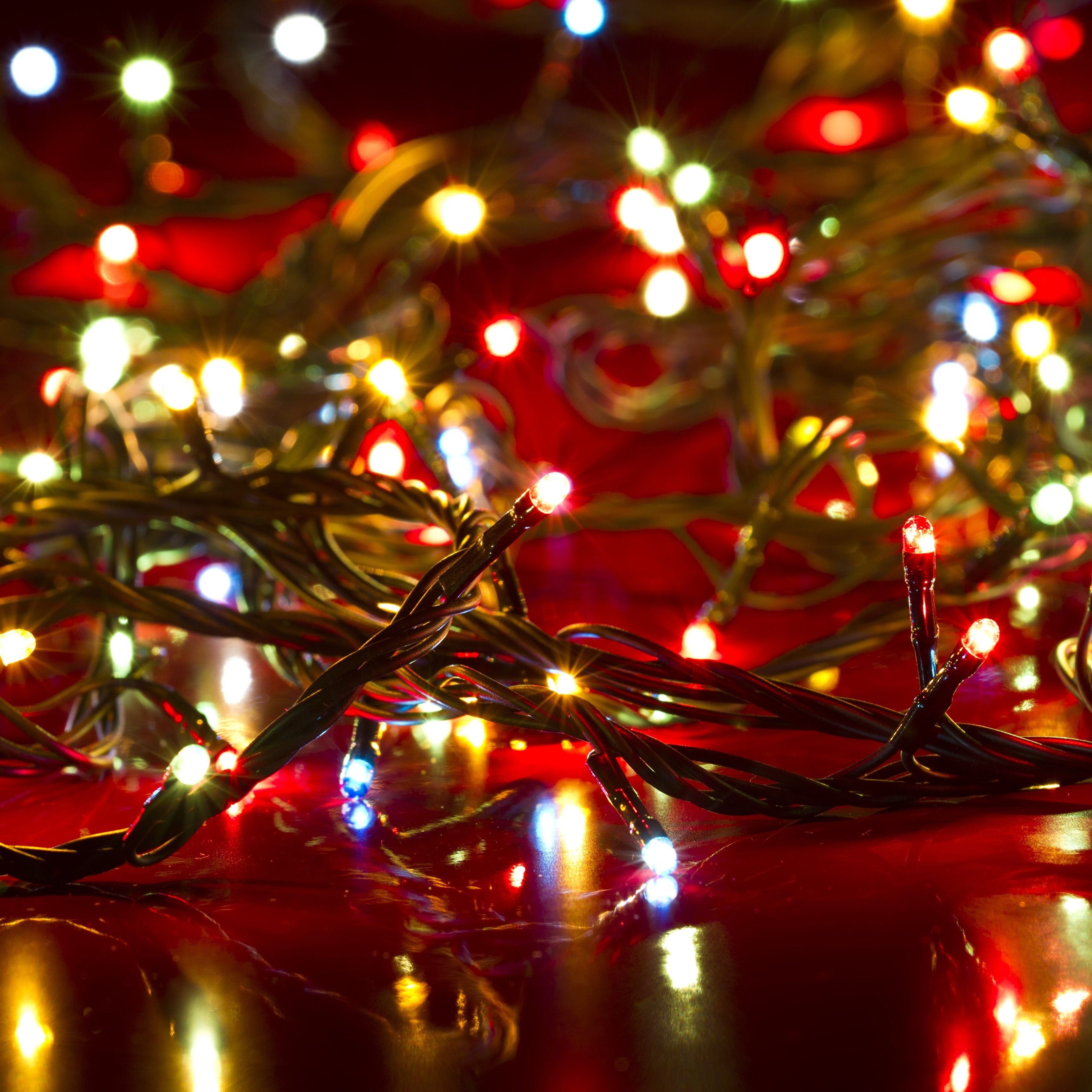 A close-up of multicolour solar fairy lights displaying various lighting modes on a red background.