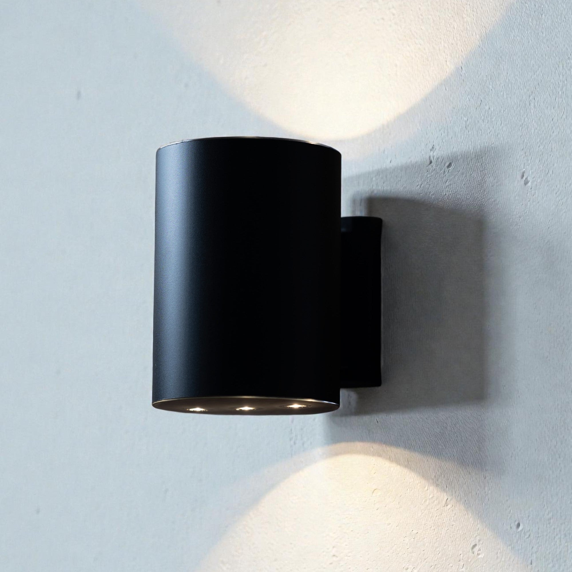 Black wall-mounted light fixture on a textured white wall
